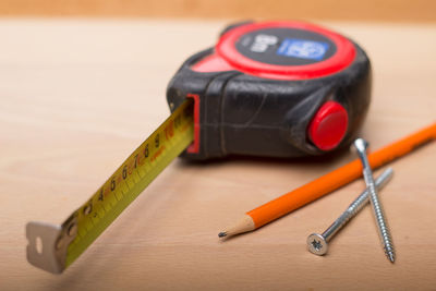 Close-up of tape measure and pencil on wooden table