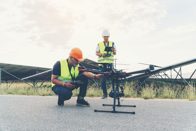 Man working with woman sitting against sky