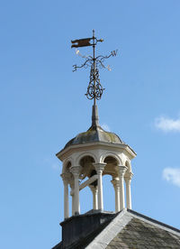 Low angle view of weather vane against blue sky