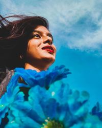 Portrait of a smiling young woman looking away against blue sky