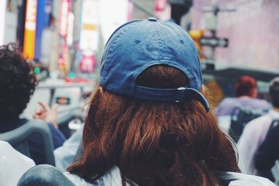 Rear view of woman wearing cap standing on street in city