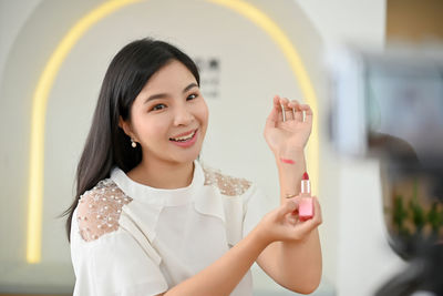 Portrait of smiling young woman standing against wall