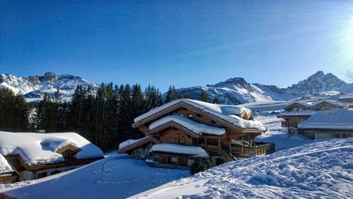 Houses by snow covered mountains against sky