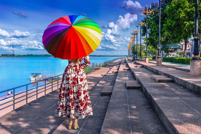 Rear view of woman with multi colored umbrella against sky