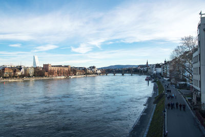 Bridge over river amidst buildings in city against sky