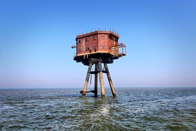 Lifeguard hut on sea against clear blue sky