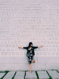 Full length of woman standing against brick wall