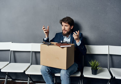 Young man sitting in box on wall