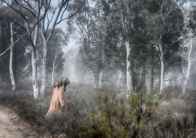 Side view of woman walking by trees in forest