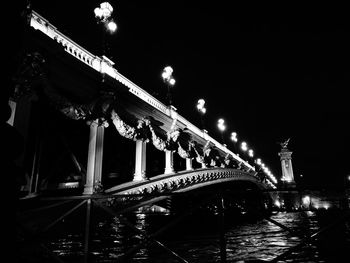 Low angle view of illuminated bridge against sky at night