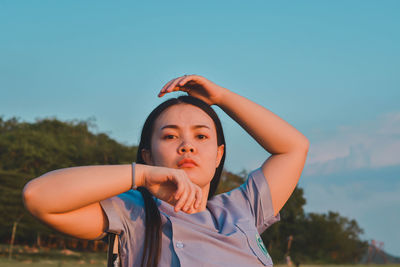 Portrait of young woman standing against sky