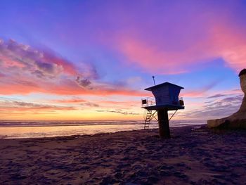 Lifeguard hut on beach against sky during sunset