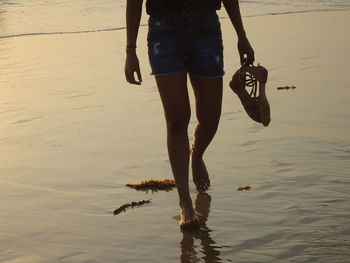 Low section of woman walking on beach