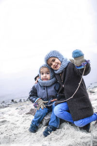 Girl in knitted grey hat sharing gloves with her frozen brother