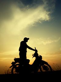 Silhouette people riding bicycle against sky during sunset