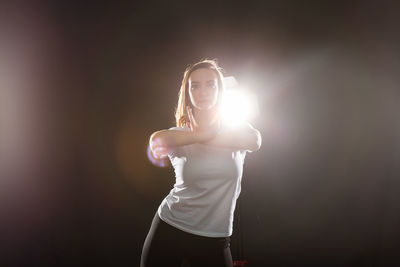 Portrait of woman standing against black background