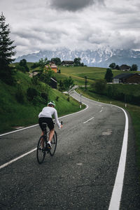 Woman riding her roadbike on road in the austrian alps under dramatic sky