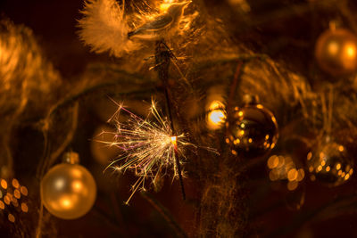 Close-up of illuminated sparkler by christmas tree