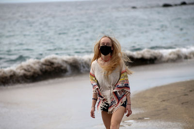 Portrait of woman wearing mask walking at beach