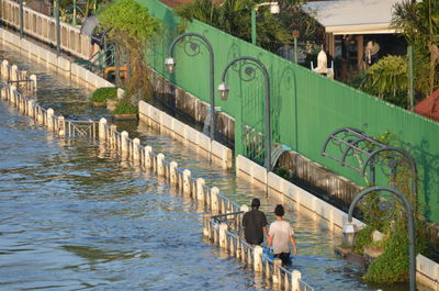 Rear view of people walking on flooded sidewalk in city
