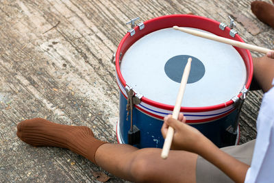 Low section of man playing drum while sitting on floor