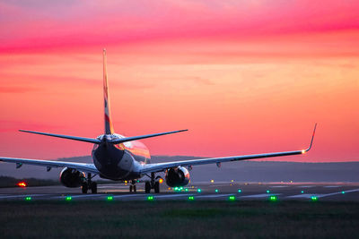 Airplane at airport runway during sunset