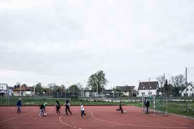 People playing basketball court against sky