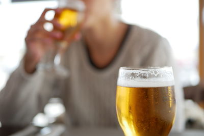 Hand holding beer glass on table