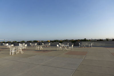 Empty chairs on field against clear sky