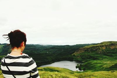 Rear view of woman standing against green landscape