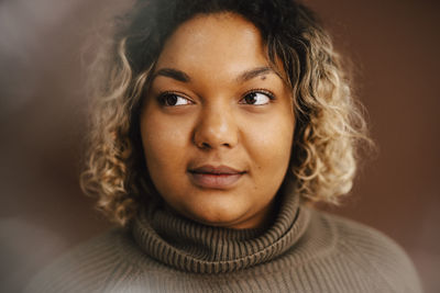 Contemplative woman over brown background in studio