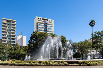 Low angle view of fountain against clear blue sky