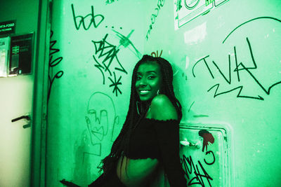 Portrait of woman standing against graffiti on wall