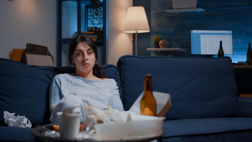 Young woman using mobile phone while sitting on bed at home