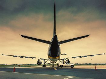 Airplane flying over airport runway against sky