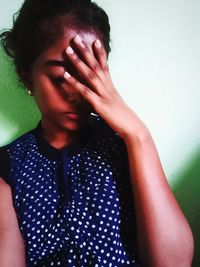 Portrait of woman covering face against wall