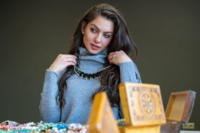 Portrait of young woman sitting against black background