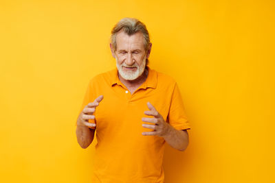 Portrait of young woman standing against yellow background