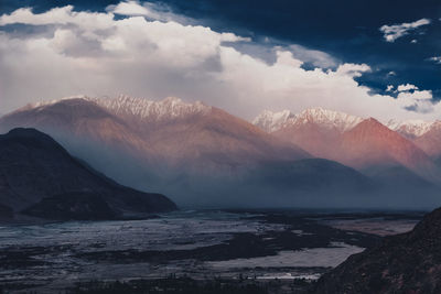 Scenic view of sea by mountains against sky