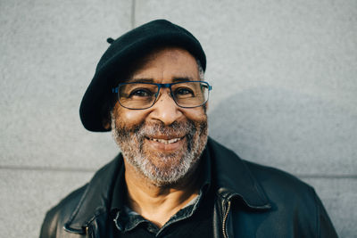 Portrait of smiling senior man against wall