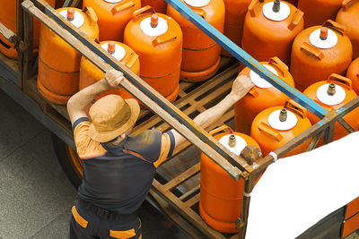 High angle view of man picking lpg cylinder from truck