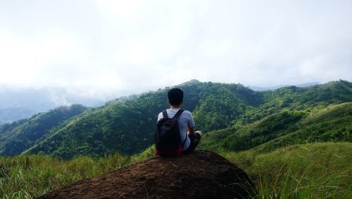 Rear view of man looking at mountain against sky