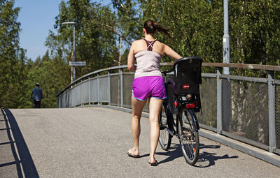 Rear view of women with umbrella on railing in city