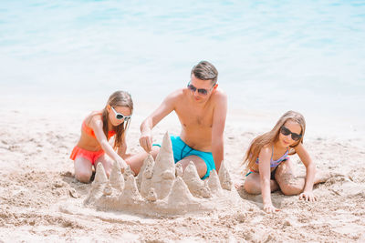 Father and daughters making sandcastle at beach