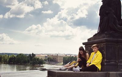 People sitting by sea against sky