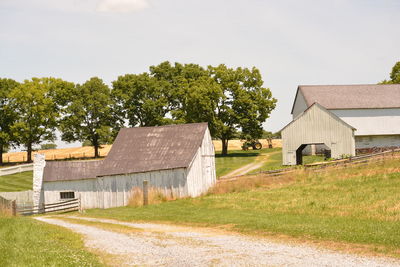 Houses by trees on field against sky