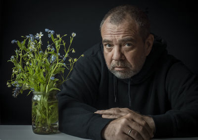 Portrait of man sitting in vase against black background