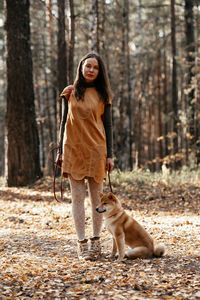 Dog walking in fall forest. beautiful woman with red backpack walking in autumn forest