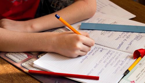 Cropped image of boy writing on book