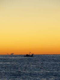 Silhouette boat in sea against clear sky during sunset